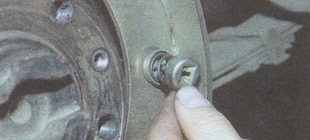 Поддерживая со стороны тормозного щита стойку прижимной пружины передней тормозной колодки нажимаем на наружную чашку пружины и, повернув её на 90°, снимаем пружину вместе с чашками