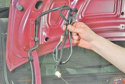 Проденьте жгут проводов и трос через отверстие в крышке багажника на автомобиле Hyundai Solaris