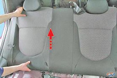 Приподнимите спинку вверх (по направлению стрелки) и извлеките спинку из салона на автомобиле Hyundai Solaris