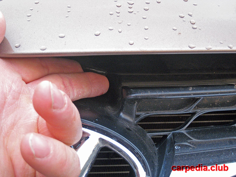 Нажать на рычаг открывания капота под крышкой капота на автомобиле Hyundai Elantra J5 MD