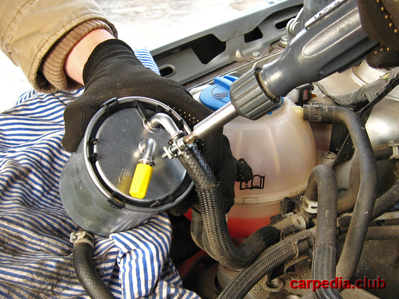 Зажать отверткой хомут крепления топливопровода топливного фильтра дизеля на автомобиле Skoda Fabia MK2 5J 2007-2014