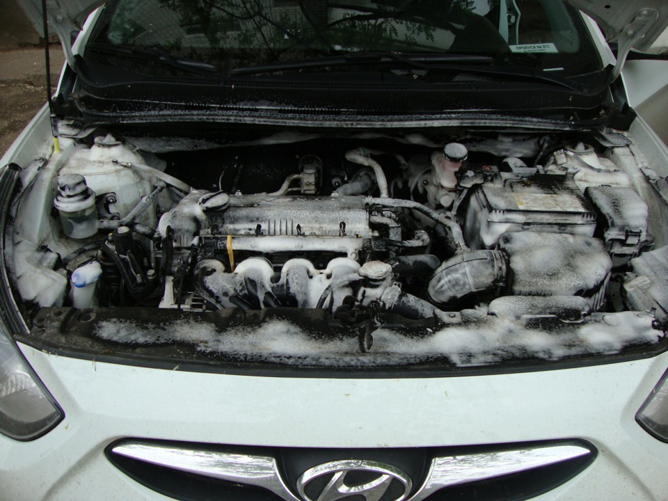 Двигатель обрабатывают специальным составом для мойки на автомобиле Hyundai Solaris