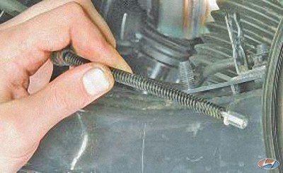 Извлеките трос привода стояночного тормоза из отверстия тормозного щита на автомобиле Hyundai Solaris