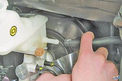 Отсоедините шланг от штуцера бачка главного тормозного цилиндра на автомобиле Hyundai Solaris