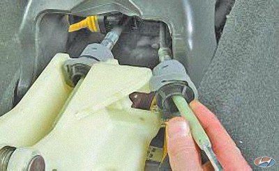 Извлеките наконечник оболочки троса переключения передач из паза в корпусе кулисы рычага управления на автомобиле Hyundai Solaris