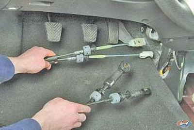 Извлеките тросы, поочередно вынимая их наконечники через отверстие в щите передка на автомобиле Hyundai Solaris