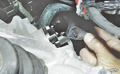 Отсоедините колодку жгута проводов в задней части коробки передач на автомобиле Hyundai Solaris