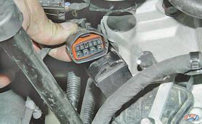 Отсоедините колодку жгута проводов в передней части коробки передач на автомобиле Hyundai Solaris