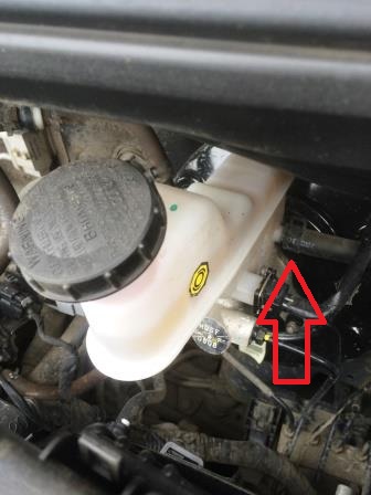 Сожмите отогнутые ушки, хомута крепления шланга подачи рабочей жидкости в главный цилиндр привода выключения сцепления на автомобиле Hyundai Solaris