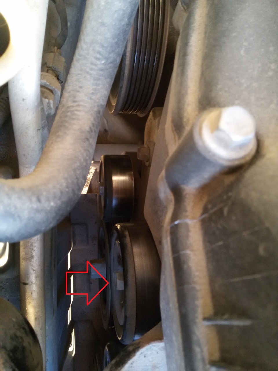 Выверните болт крепления вспомогательного ролика ремня привода вспомогательных агрегатов на автомобиле Hyundai Solaris