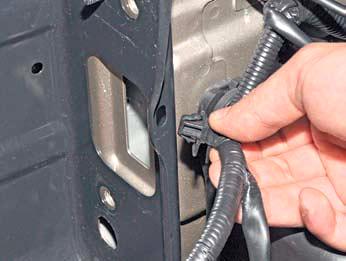 Выводим держатель переднего жгута проводов из отверстия рамки радиатора на автомобиле Hyundai Solaris