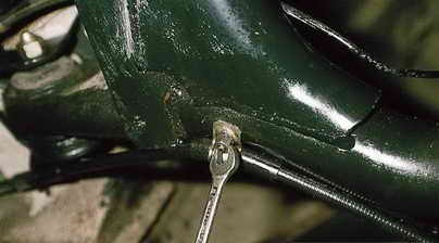 Откручивание крепления троса стояночного тормоза к балке задней подвески Лада Гранта (ВАЗ 2190)