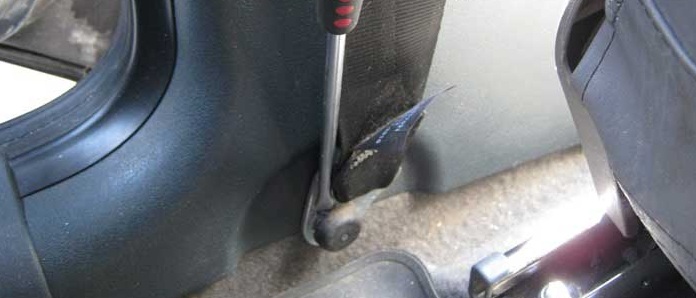 Подденьте отверткой и снимите пластмассовую накладку болта нижнего крепления ремня безопасности на автомобиле Лада Гранта