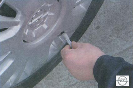 Отворачивание колпачка вентиля на автомобиле Opel Astra