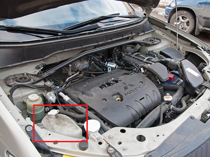 Расположение расширительного бачка системы охлаждения двигателя Mitsubishi Outlander XL II 2007 - 2012