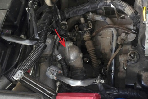Размещение места возможной утечки охлаждающей жидкости на стыке крышки термостата двигателя 4B12 Mitsubishi Outlander XL