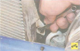Отворачивание болта левого крепления радиатора кондиционера Renault Logan
