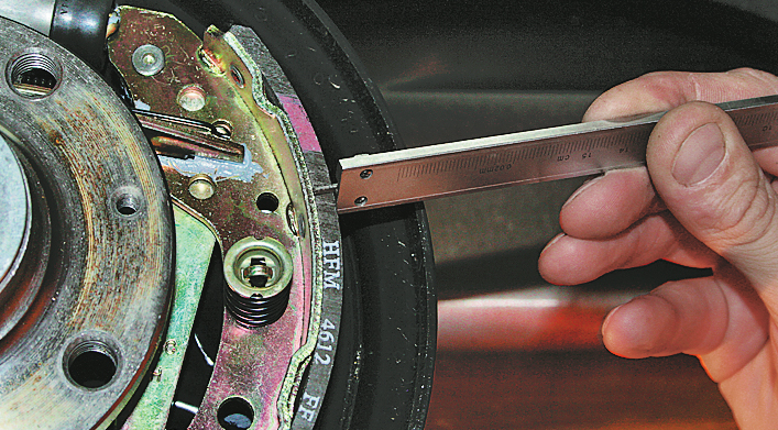 Измерьте толщину фрикционных накладок колодок барабанного тормозного механизма задних колес на автомобиле Hyundai Solaris