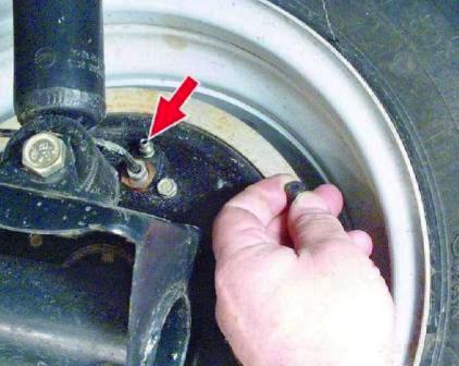 Очистите от грязи клапаны выпуска воздуха и снимите защитные колпачки клапанов рабочих цилиндров тормозных механизмов задних колес на автомобиле Hyundai Solaris