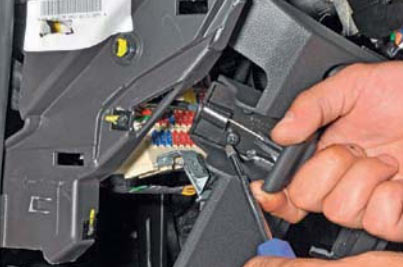 Отворачиваем два винта крепления ручки открывания капота к нижней декоративной накладке панели приборов на автомобиле Hyundai Solaris