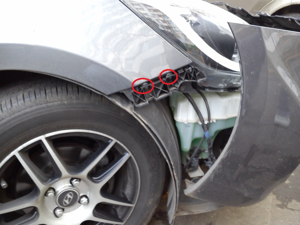 Под держателем переднего бампера выверните два болта крепления крыла к кузову на автомобиле Hyundai Solaris