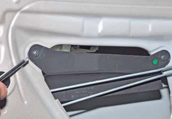 Отворачиваем два самореза крепления пластмассового прижима тяг внутренней ручки двери на автомобиле Hyundai Solaris
