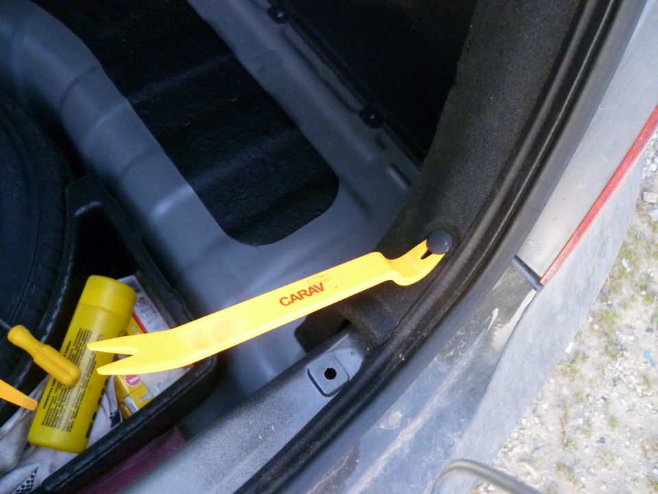 Подденьте лопаткой и снимите пять пластмассовых держателей крепления боковой облицовки багажника на автомобиле Hyundai Solaris