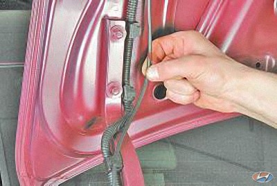 Извлеките из держателя трос привода крышки багажника на автомобиле Hyundai Solaris