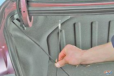 Отсоедините трос привода крышки багажника на автомобиле Hyundai Solaris