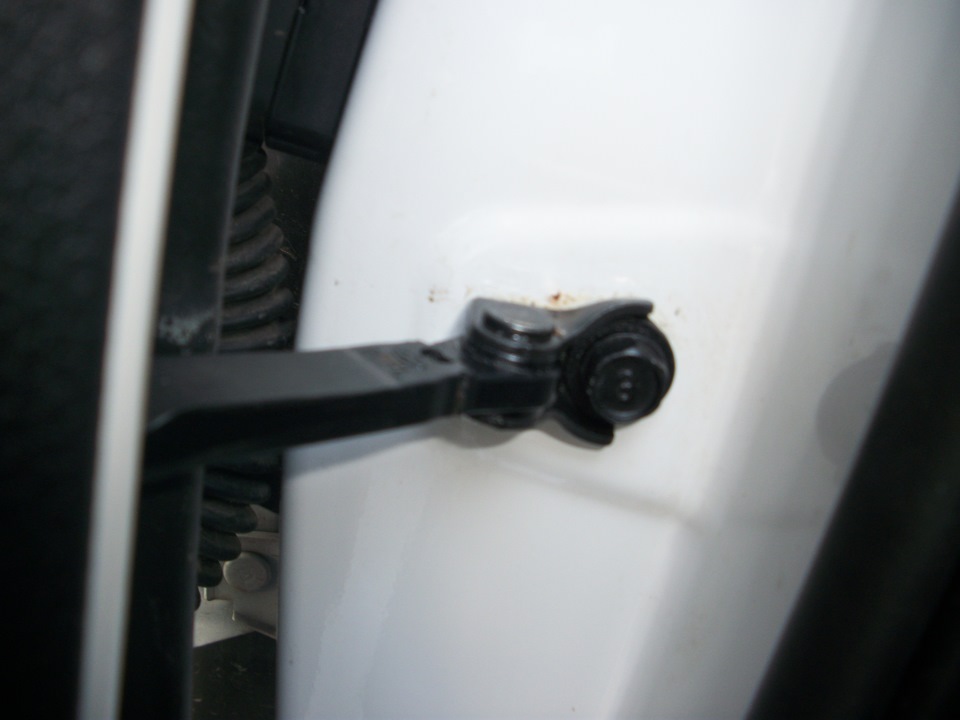 Выверните болт крепления ограничителя двери к передней стойке кузова, как описано здесь на автомобиле Hyundai Solaris