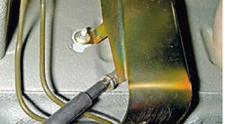 Вынимание левого троса стояночного тормоза из защитного экрана топливопровода Lada Kalina