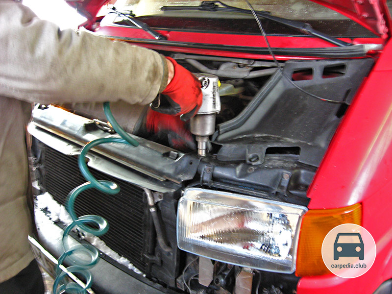 Отворачивание левого болта крепления верхней планки радиатора Volkswagen Transporter T4