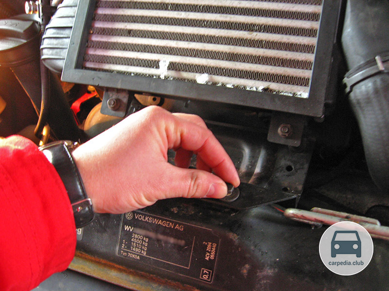 Отворачивание болта крепления пластины охладителя воздуха к верхней планке радиатора Volkswagen Transporter T4
