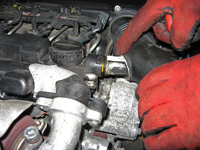 Извлечение патрубка воздушного рукава из отверстия в двигателе Peugeot 207