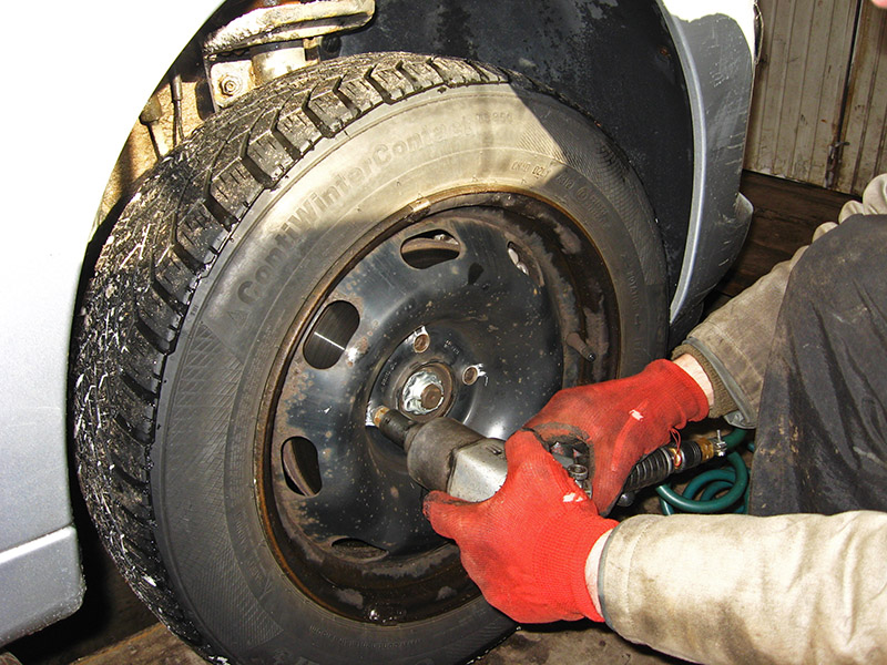 Выкручивание болтов крепления переднего колеса автомобиля Peugeot 207