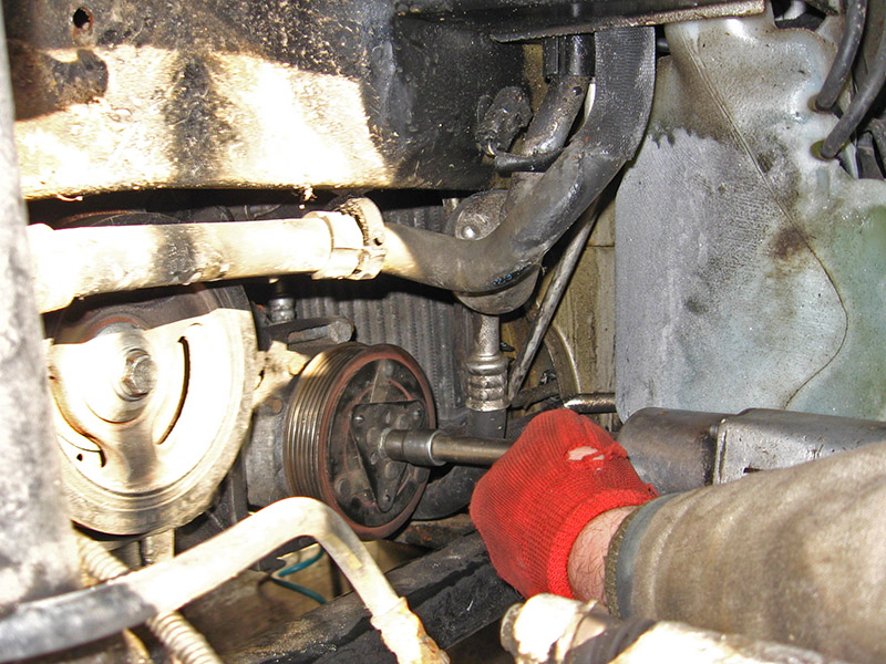 Откручивание гайки крепления опорной пластины компрессора кондиционера Peugeot 207