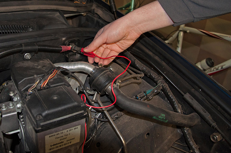 Закрепите положительный зажим кабеля зарядного устройства на плюсовом выводе автомобиля BMW X5 I E53 1999 - 2006