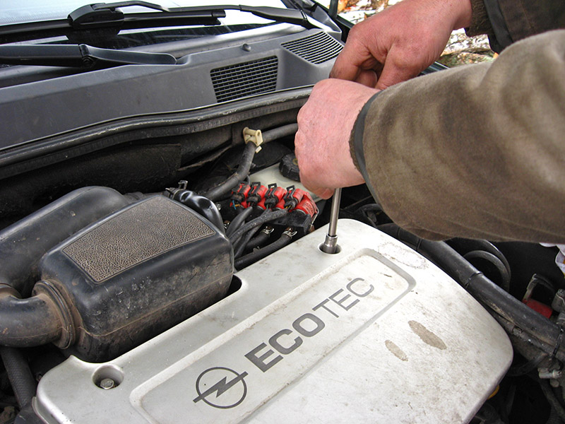 Выворачивание винта крепления декоративного кожуха к крышке головки блока цилиндров двигателя Opel Astra II G