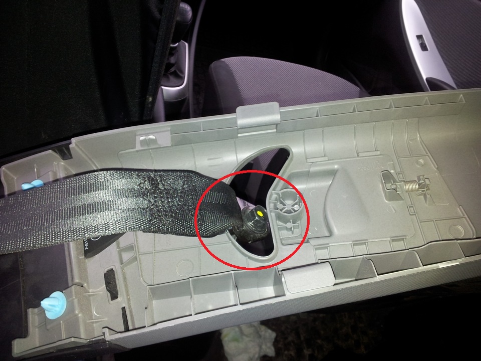 Проденьте через отверстие в облицовке язычок нижнего крепление ремня безопасности на автомобиле Hyundai Solaris