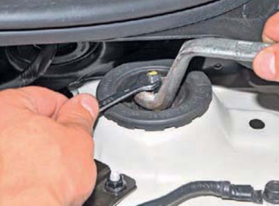 Ослабьте затяжку гайки верхнего крепления амортизаторной стойки на автомобиле Hyundai Solaris