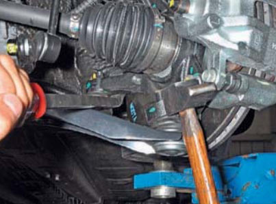 Наносим удары молотком по проушине поворотного кулака на автомобиле Hyundai Solaris