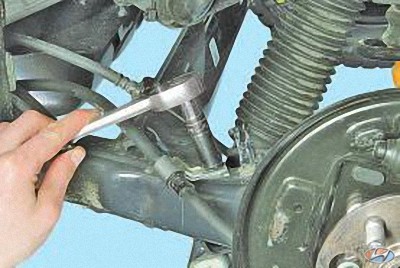 Отверните гайку и отсоедините кронштейн крепления троса привода стояночного тормоза на автомобиле Hyundai Solaris