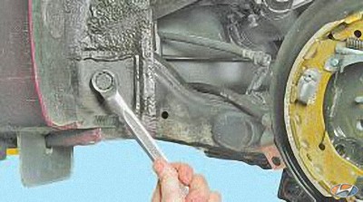 Выверните болт крепления балки задней подвески к кузову на автомобиле Hyundai Solaris