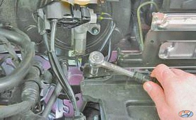 Выверните болты крепления кронштейна электронного блока к полке аккумуляторной батареи на автомобиле Hyundai Solaris