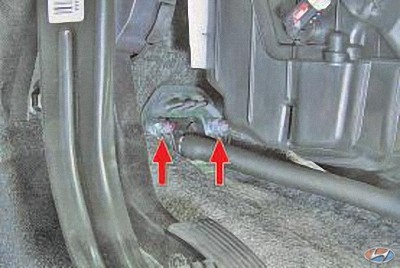 Выверните два болта крепления кронштейна тросов к щиту передка автомобиля Hyundai Solaris