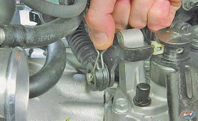 Извлеките шплинт крепления наконечника троса из отверстия оси рычага выбора передач на автомобиле Hyundai Solaris