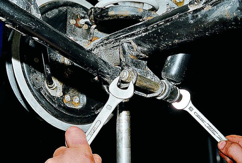 Откручивание и снятие гайки нижнего крепежного болта амортизатора задней подвески к кронштейну рычага Volkswagen Polo