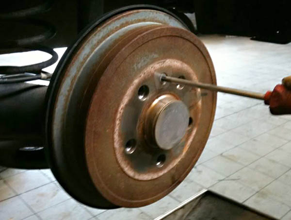 Отворачивание винта крепления барабана к ступице тормозного барабанного механизма заднего колеса автомобиля Skoda Fabia I