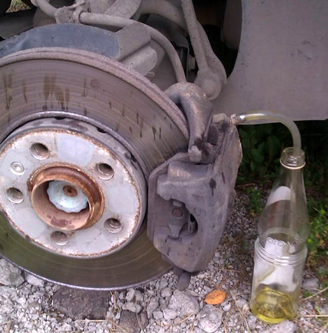 Слив тормозной жидкости через трубку на переднем колесе автомобиля Skoda Fabia I