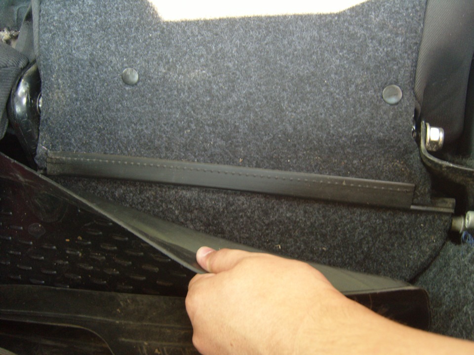 Отсоединяем крючки, соединяющие ковер багажного отделения, с ковром на спинке сидений Fiat Doblo